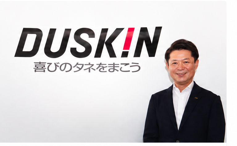 ダスキンのロゴが掲げられた壁の前に立つ担当者